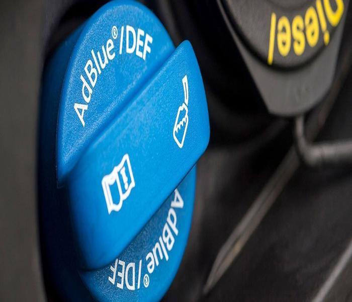 AdBlue filler cap next to a diesel fuel cap on a vehicle